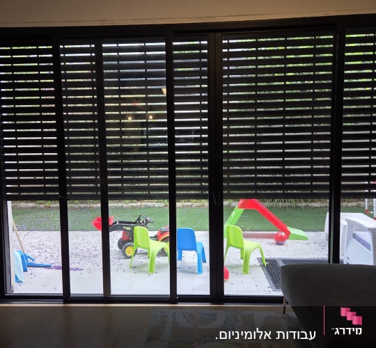 תריסי אלומיניום שחורים על חלון זכוכית גדול